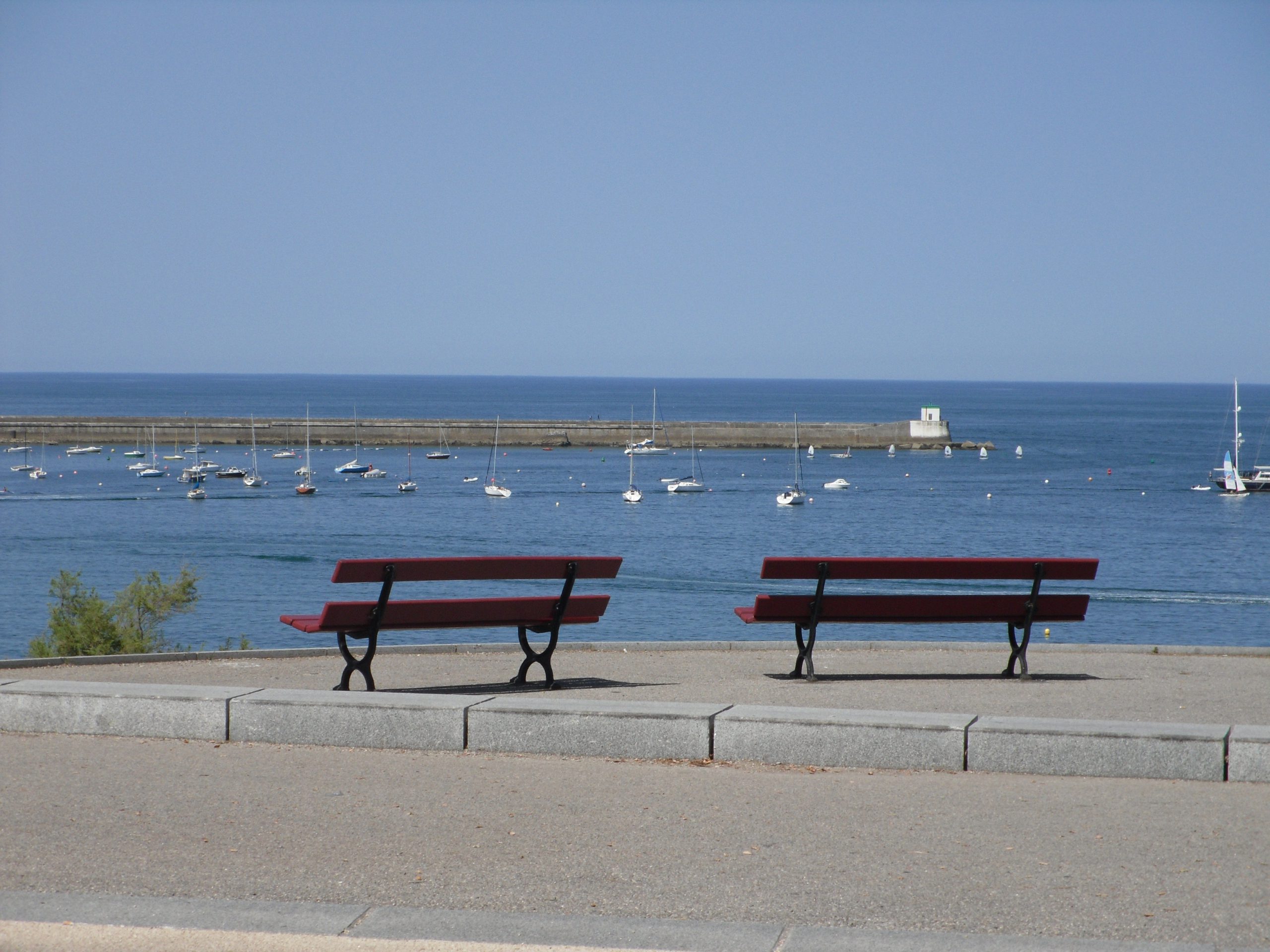 Deux bancs côte à côte au bord de la mer, représentant la relation de couple et le dialogue